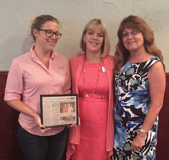 women holding framed newspaper article