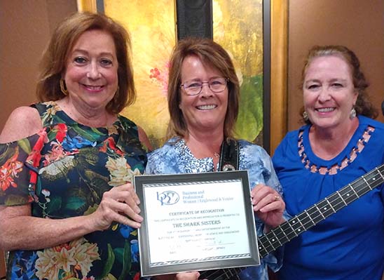 Three female band members holding plaque